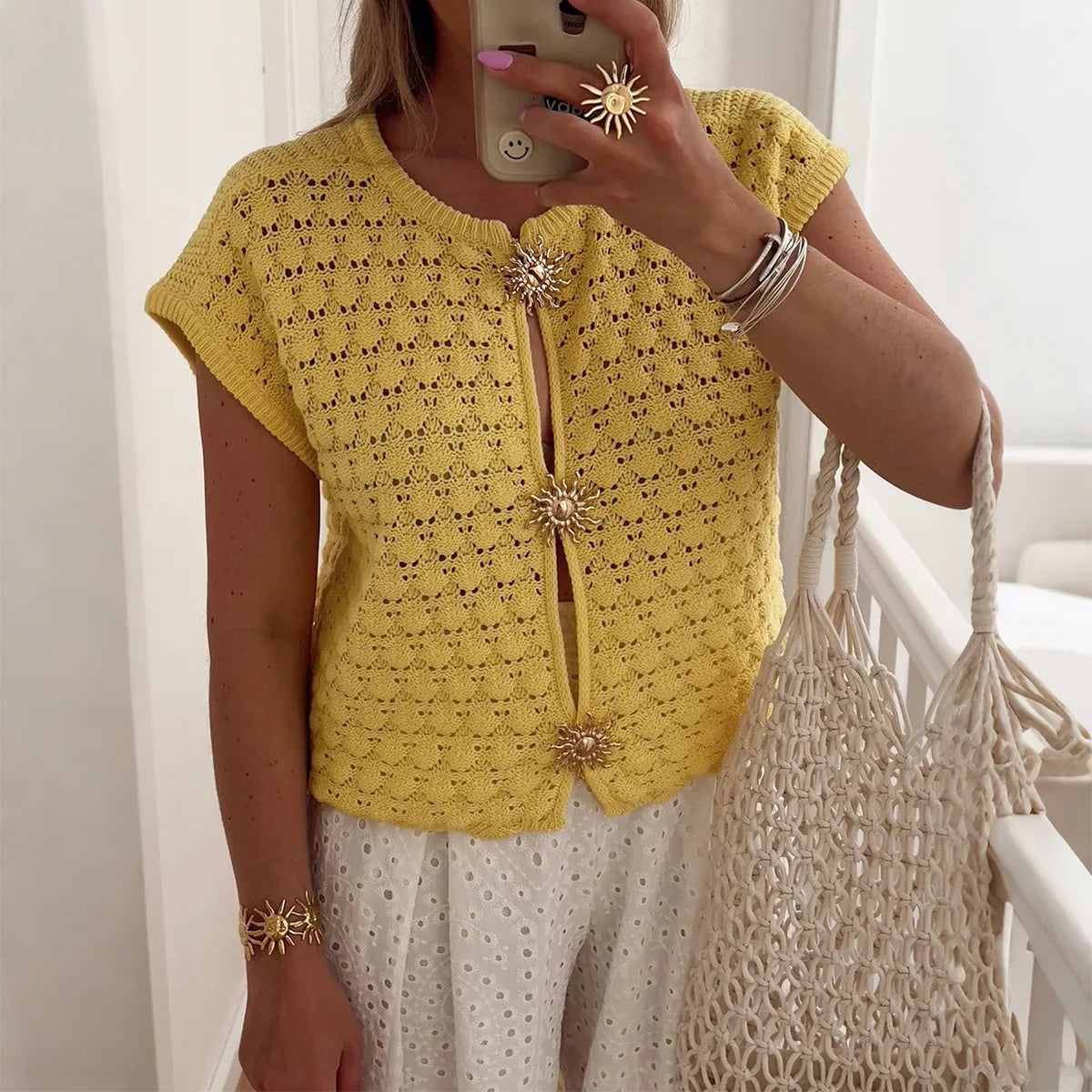 Women's white crochet knit cropped blouse with relaxed silhouette and sunburst floral buttons