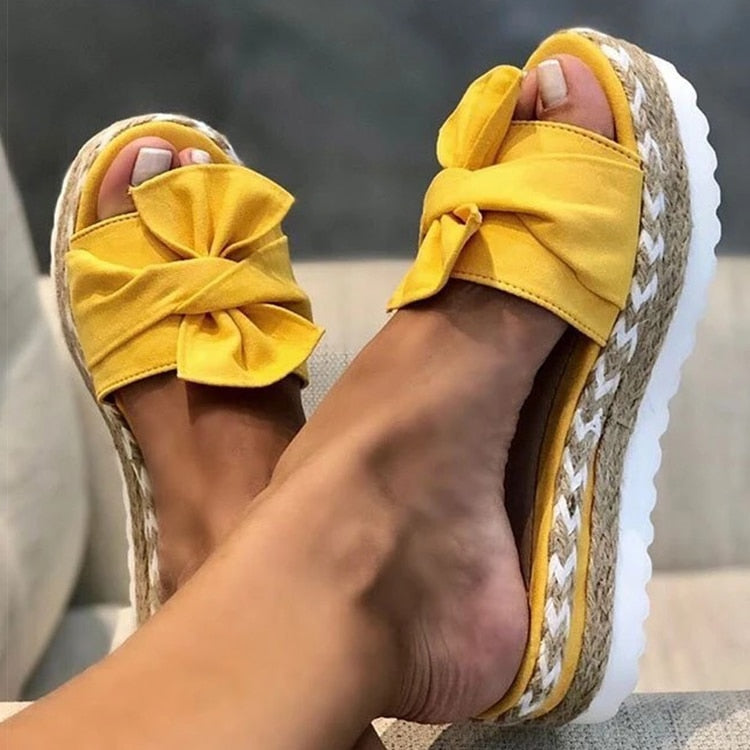 Women's vibrant yellow platform slides with braided sole and oversized bow, bold summer style