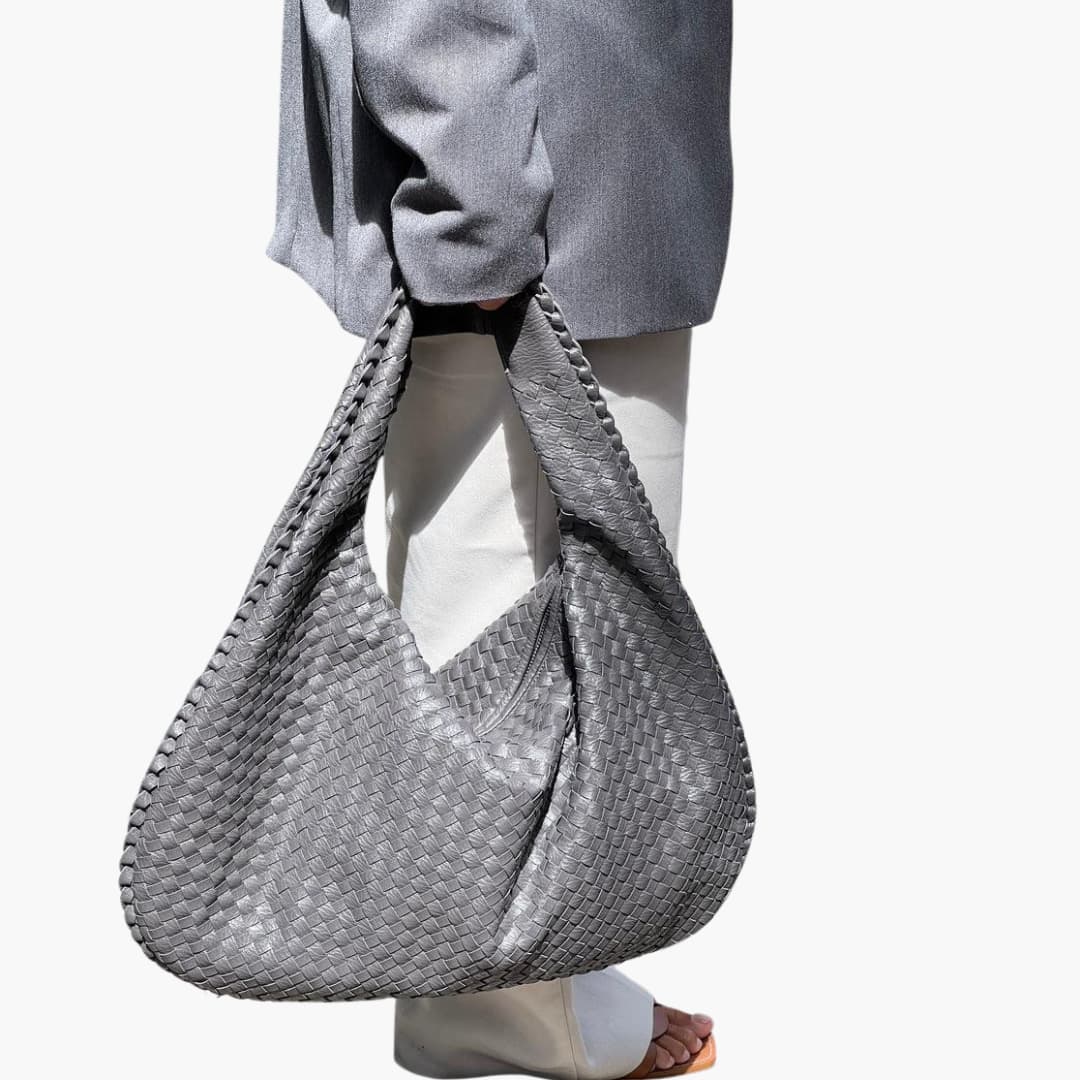 Women's braided woven shoulder bag with structured strap, textured exterior, and secure top zipper closure