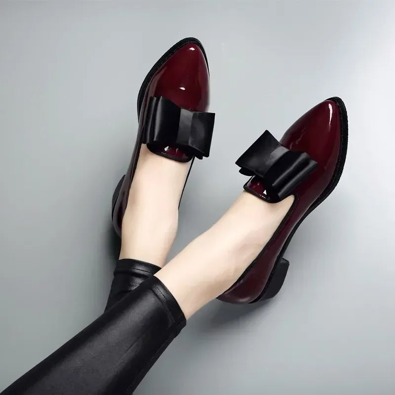 Women's black patent leather pumps with bold bow tie vamp detail, sleek office-to-evening style