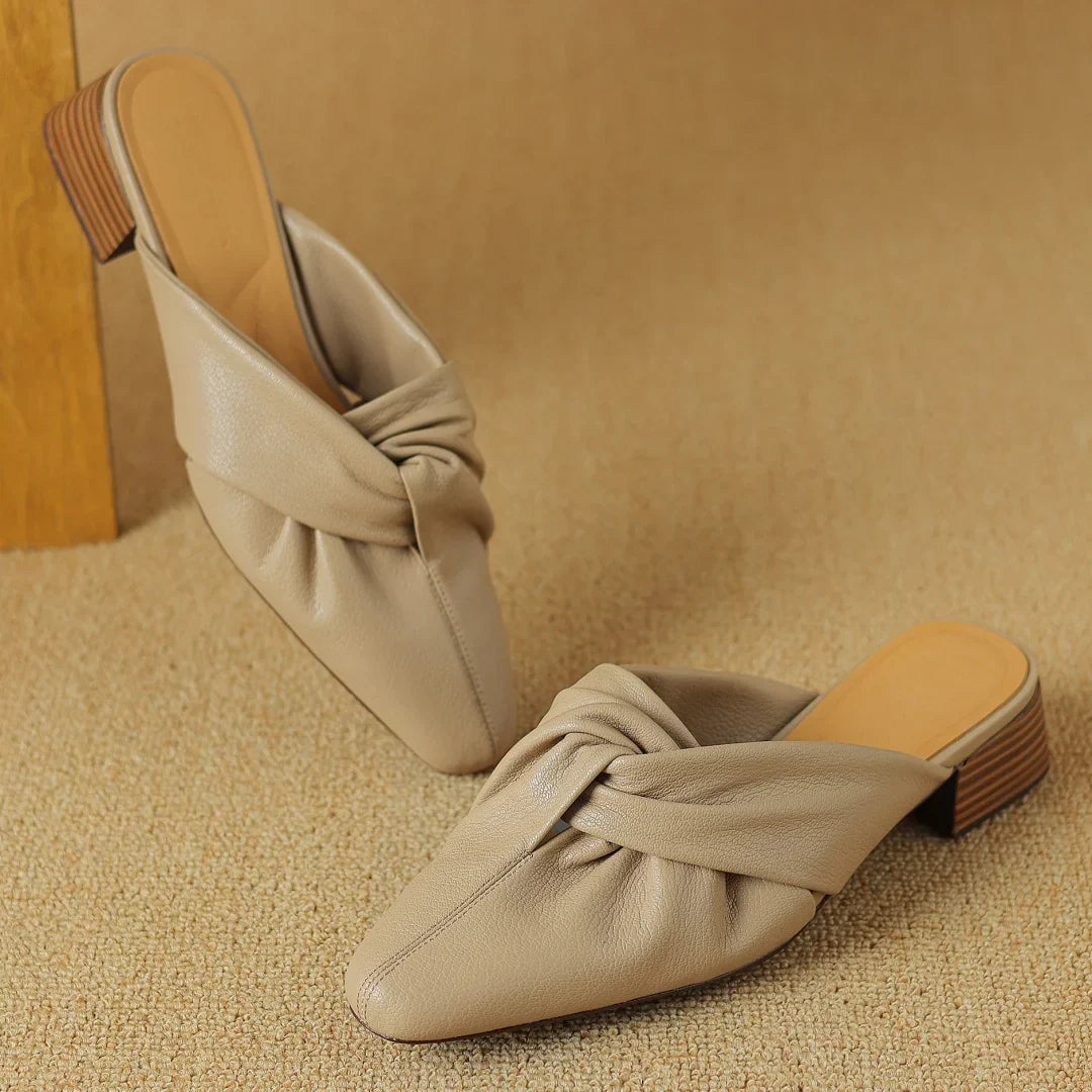 Genuine leather mules with signature bow-knot detail, textured finish, slip-on style for modern women