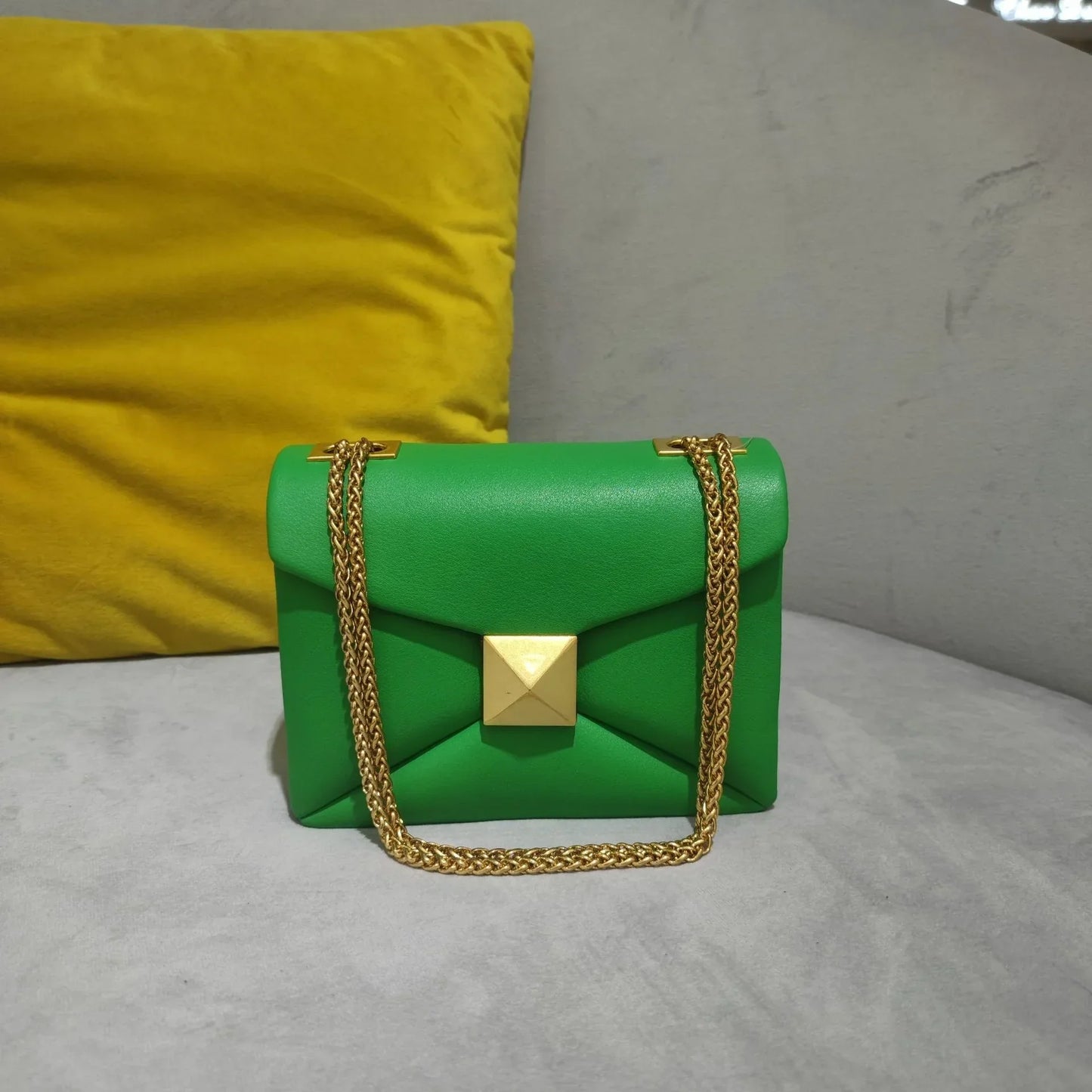 Women's faux leather envelope crossbody bag with rivet hardware detailing and gold chain strap