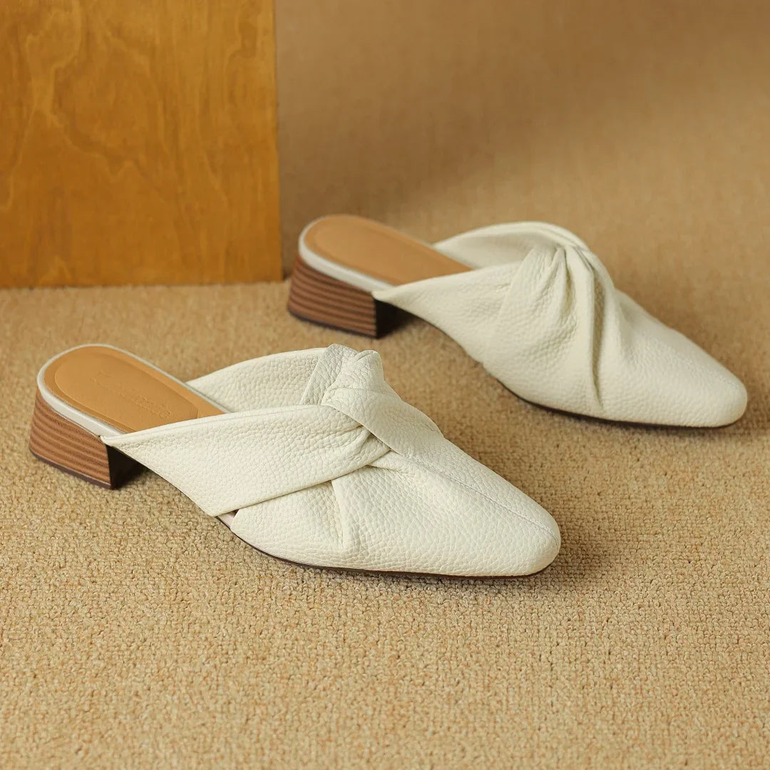Genuine leather mules with signature bow-knot detail, textured finish, slip-on style for modern women