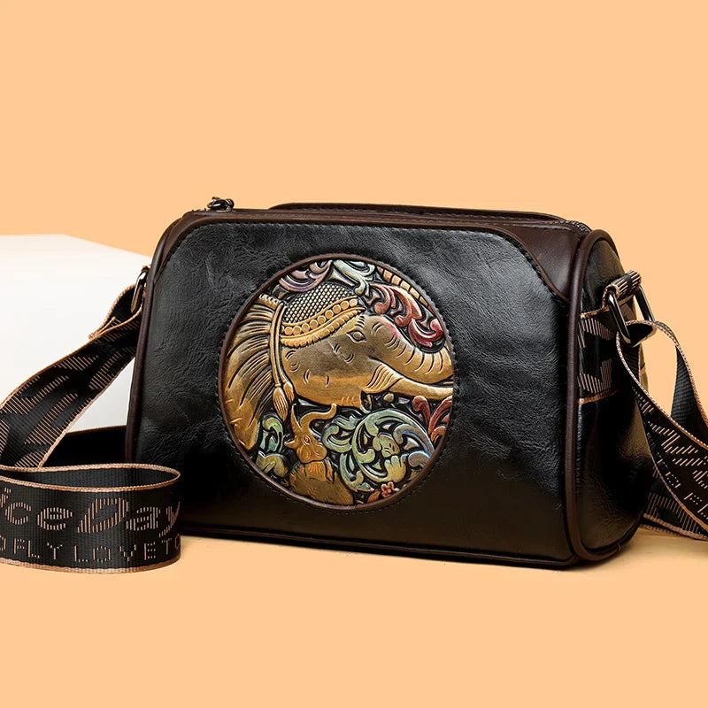 Brown leather shoulder bag with embossed circular elephant motif, blending artisan detail and everyday style