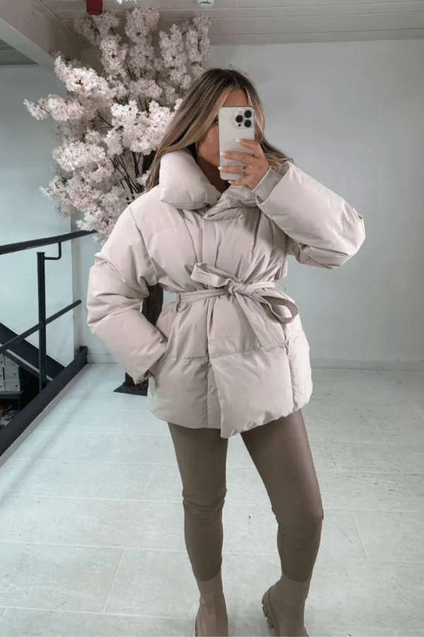 Women's belted puffer jacket with high collar, cozy padding, and flattering silhouette in winter style