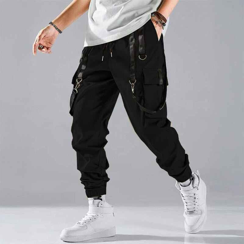 Black cargo trousers with tactical pockets, harness details, and adjustable buckle straps for streetwear