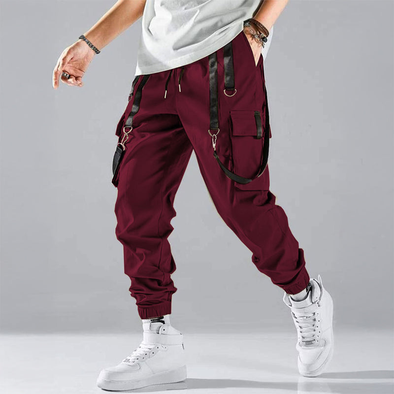 Black cargo trousers with tactical pockets, adjustable buckle straps, and harness details for streetwear