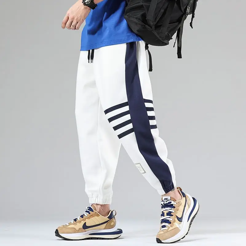 Navy blue dual-tone color block varsity joggers with contrast stripe panels and elastic cuffs