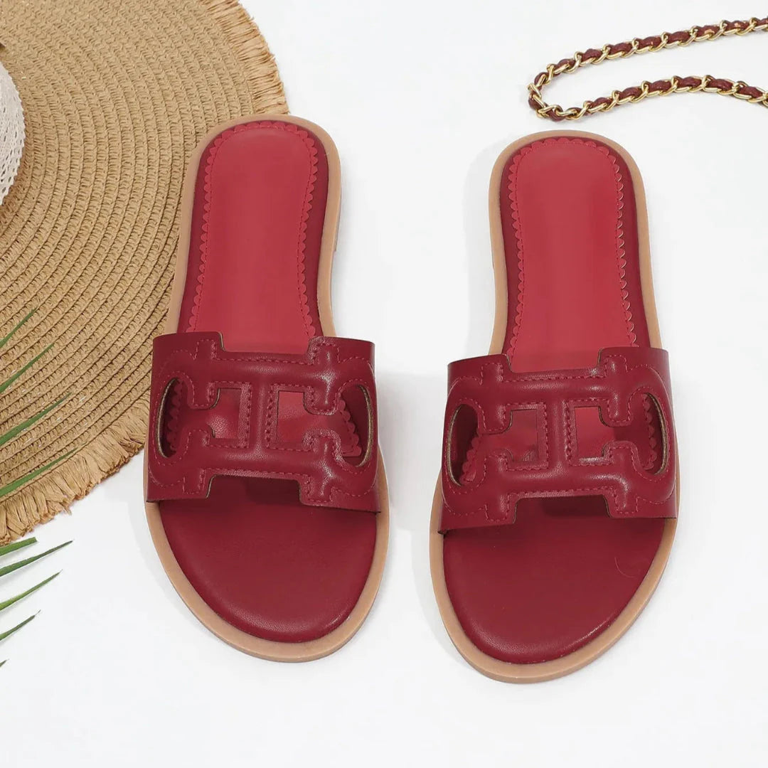 Women's black faux leather cutout slides with bold strap and vibrant red cushioned footbed