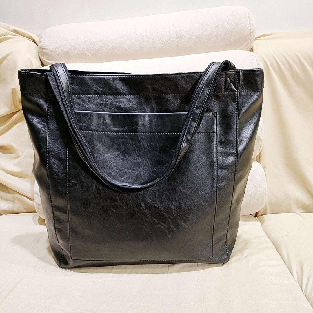 Women's black faux leather double-strap tote bag with minimal silhouette and rich natural texture