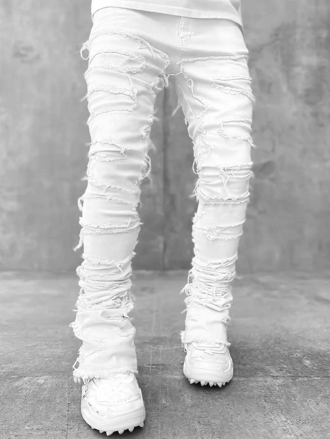 Blue distressed stretch denim tapered jeans with heavy fraying and reinforced layered seams