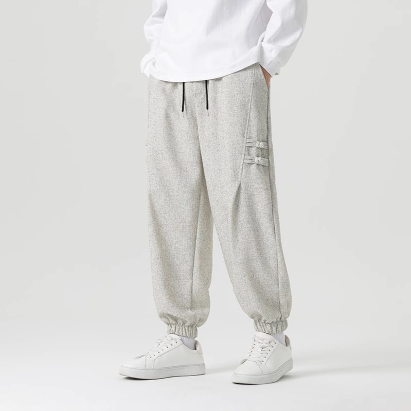Light gray minimalist joggers with tailored drape, breathable fabric, and traditional side knot details