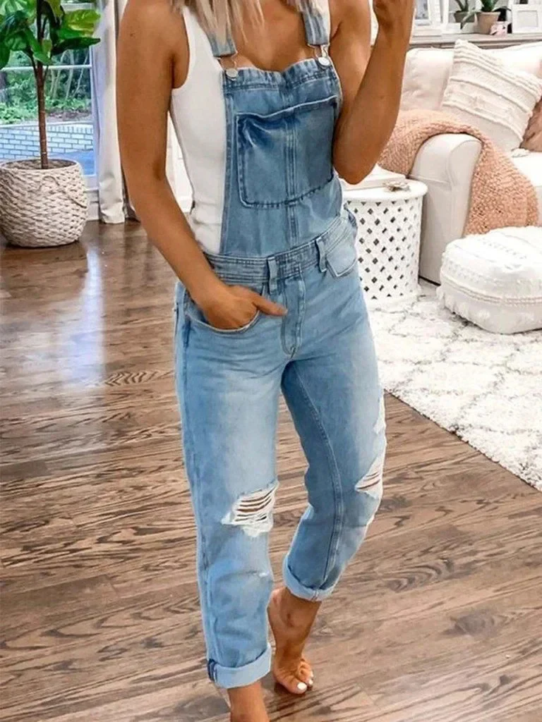 Women's relaxed-fit blue denim jumpsuit with adjustable straps and distressed knee details