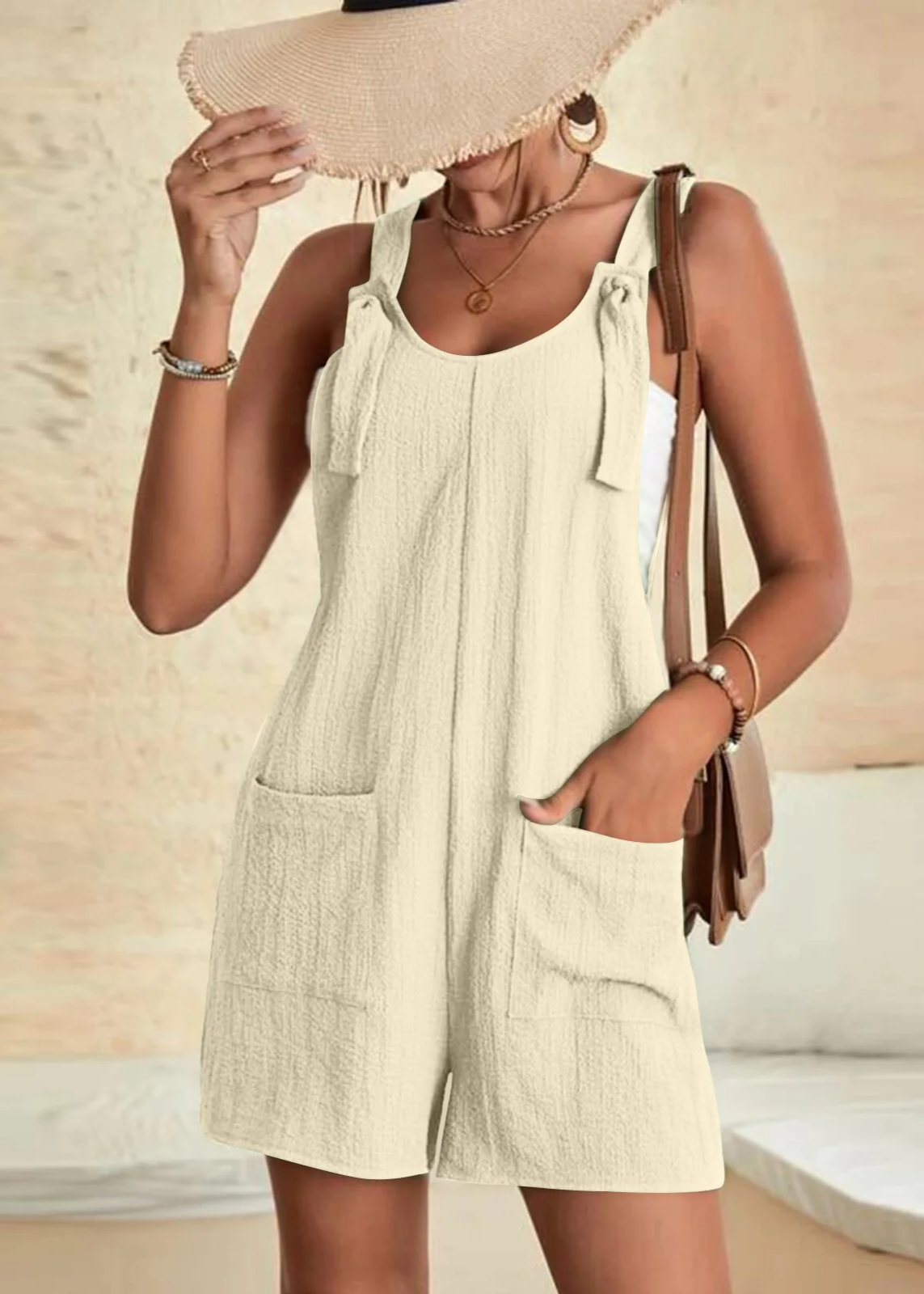 Women's beige cotton-blend lounge romper with adjustable bow straps, relaxed fit, and side pockets