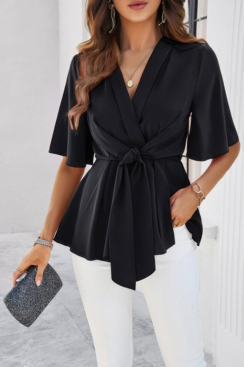 Women's white v-neck peplum blouse with tie front, bell sleeves, and cinched waist silhouette