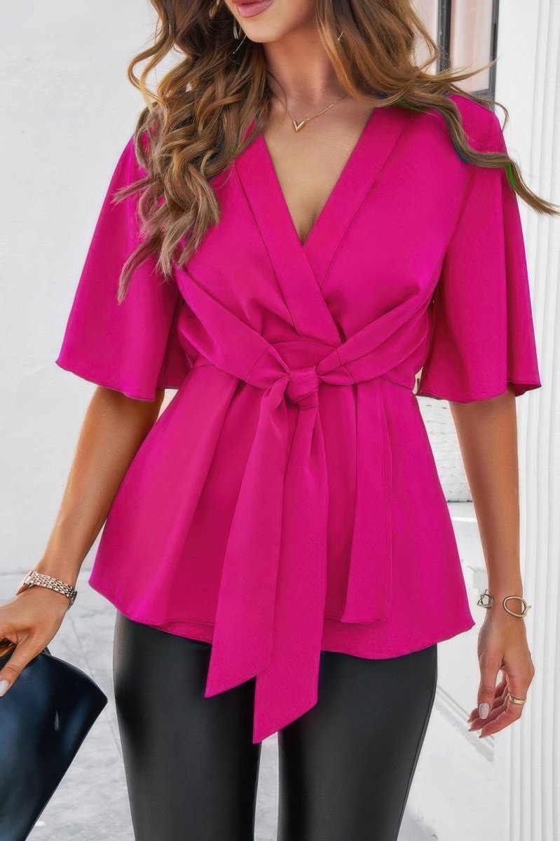 Women's white v-neck peplum blouse with tie front, bell sleeves, and cinched waist silhouette