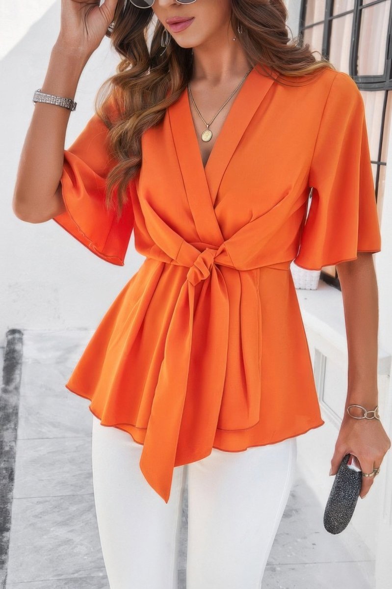 Women's white v-neck peplum blouse with tie front, bell sleeves, and cinched waist silhouette