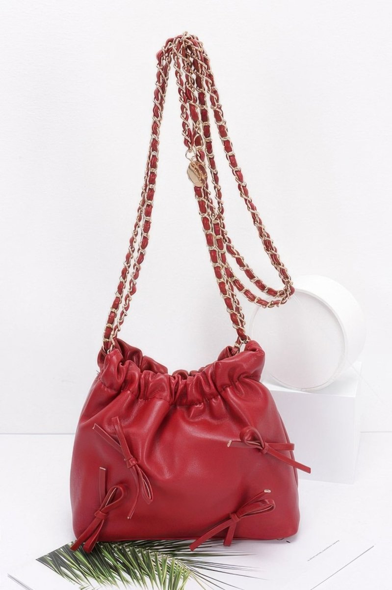 Black faux leather bucket crossbody bag with ribbon embellishment, gold chain strap, cinched closure