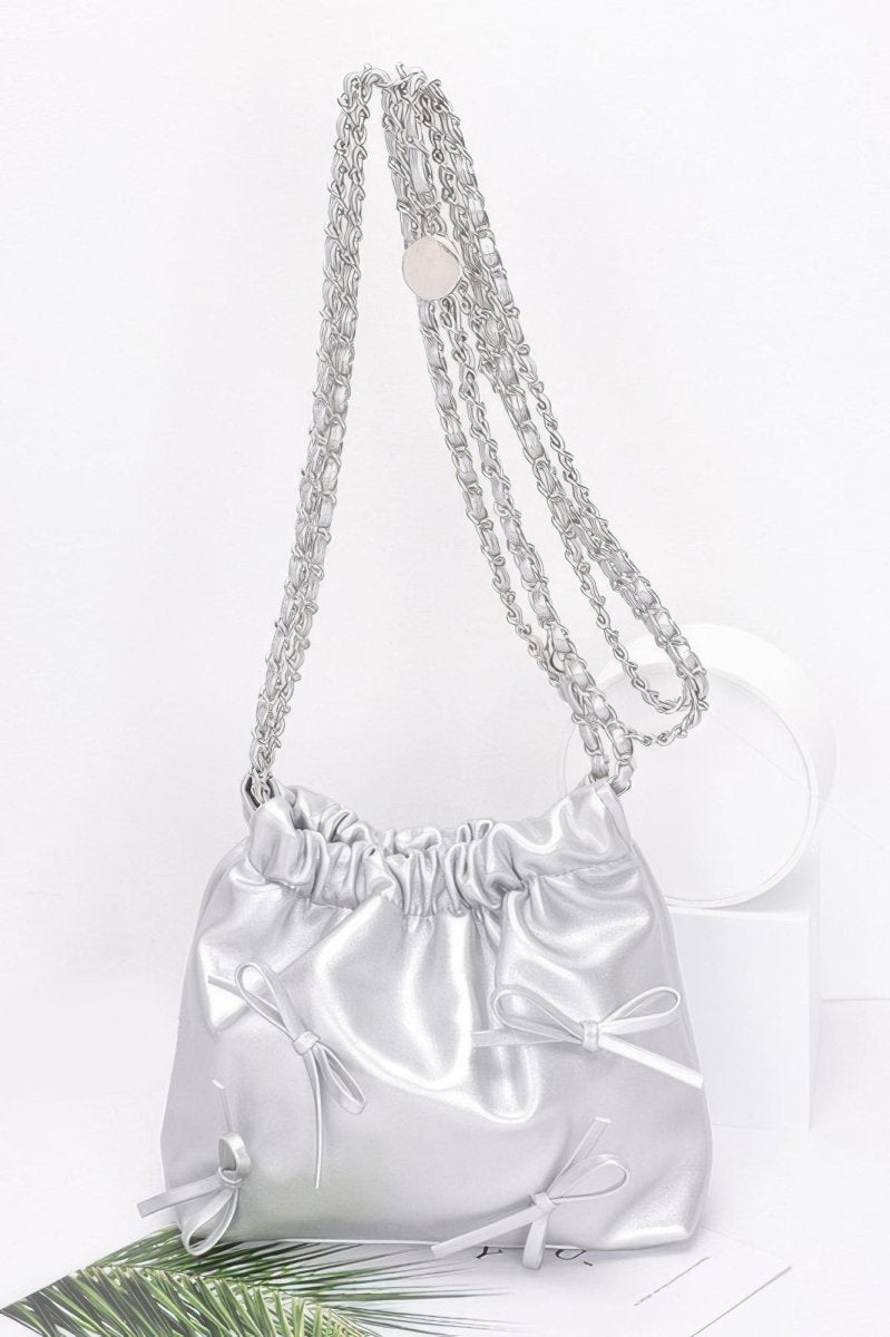Black faux leather bucket crossbody bag with ribbon embellishment, gold chain strap, cinched closure