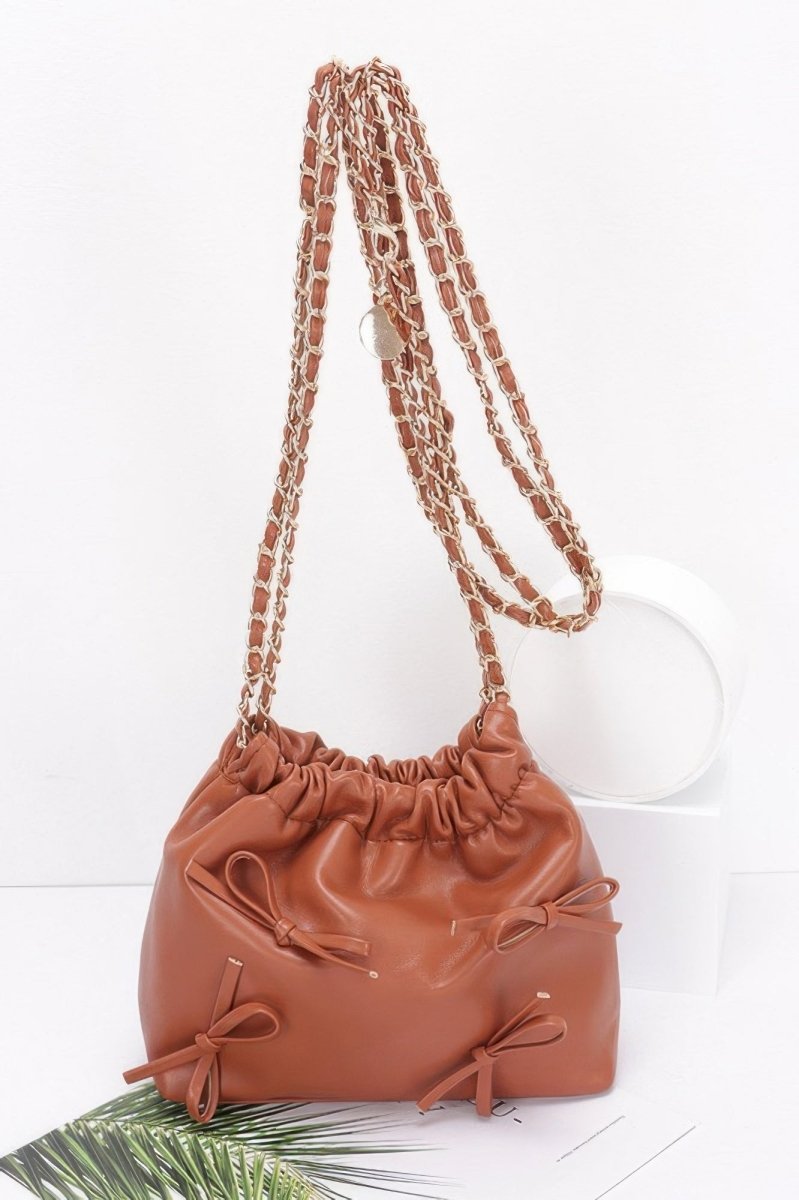 Black faux leather bucket crossbody bag with ribbon embellishment, cinched closure and gold chain strap