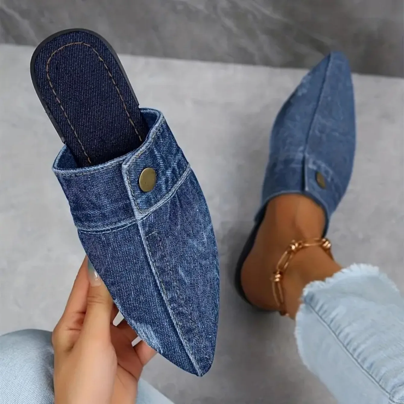 Women's denim mule slide with cushioned footbed, stitched seam detailing, and brass button accent