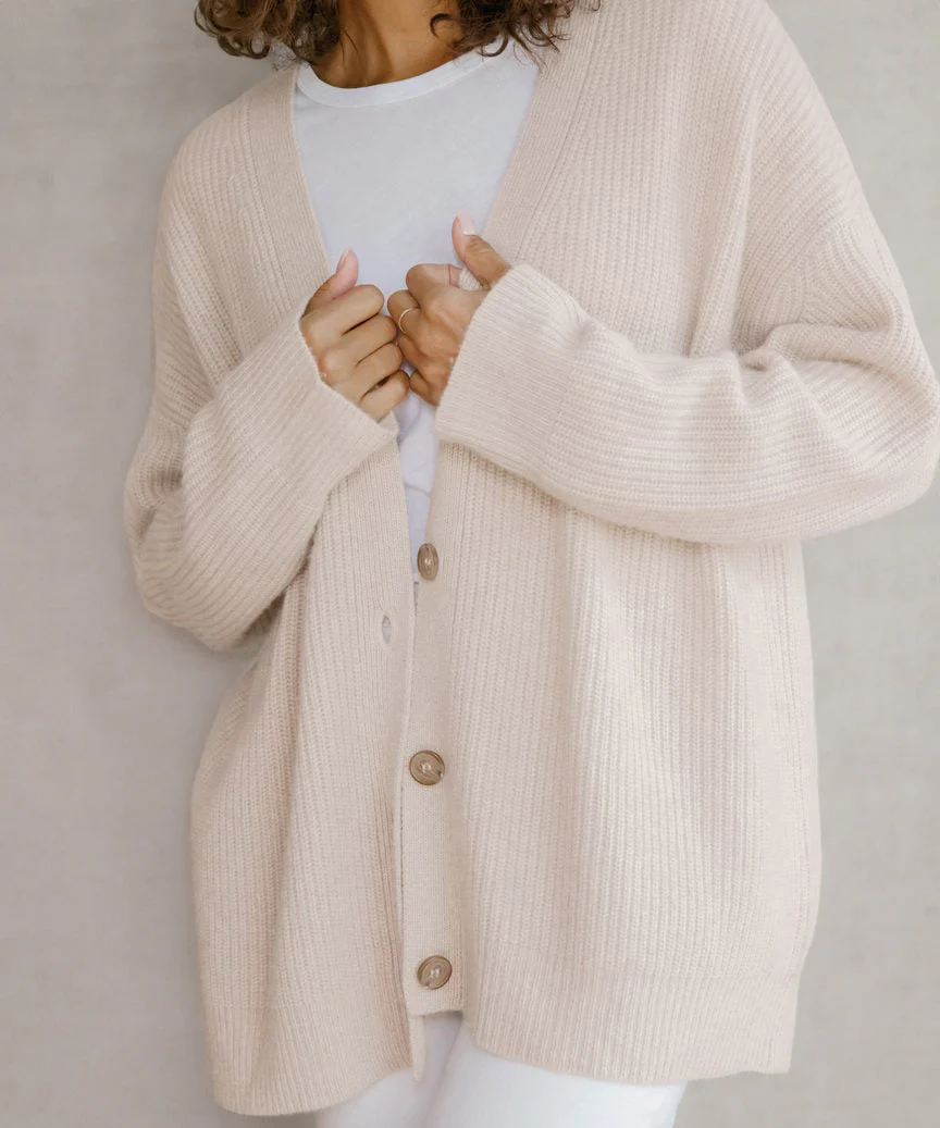 Women's chunky knit V-neck cardigan in neutral tones, relaxed hip-length silhouette with button front