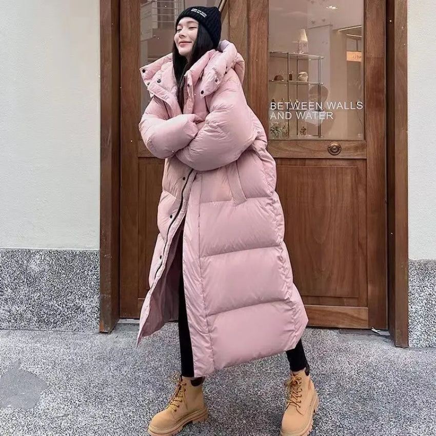 Women's long oversized down jacket with hood, cozy elegant winter style in soft neutral tones