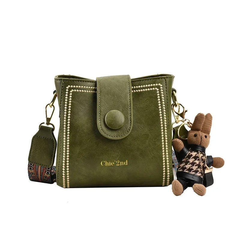 Vintage messenger crossbody bag with wide adjustable strap, muted tones and retro metal-finish hardware