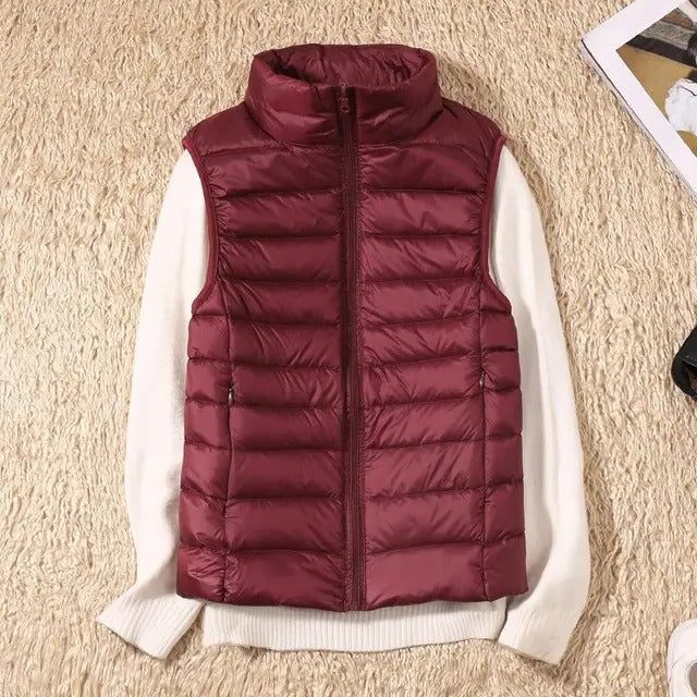 Women's lightweight sleeveless puffer vest in neutral tone, packable insulated layering essential for travel