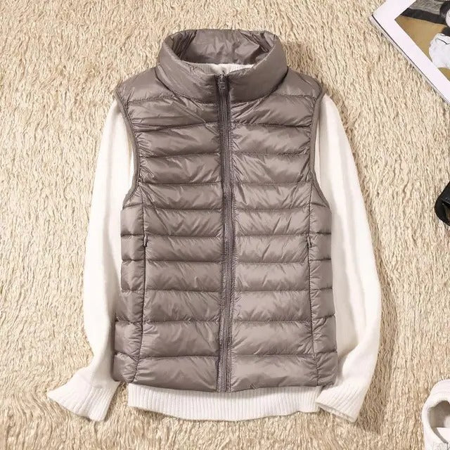 Women's lightweight sleeveless puffer vest in neutral tone, packable insulated layering style for travel