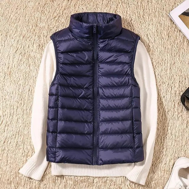 Women's lightweight sleeveless puffer vest in neutral tone, packable insulated layering essential for travel