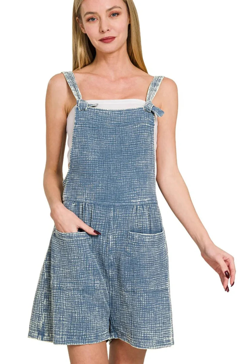Women's light blue smocked denim romper with adjustable straps and pockets, relaxed summer fit