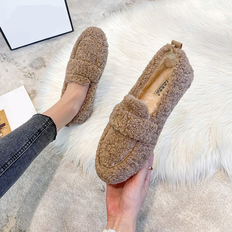 Women's plush slip-on slippers in cozy neutral tone with padded interior and flexible sole for indoor outdoor use