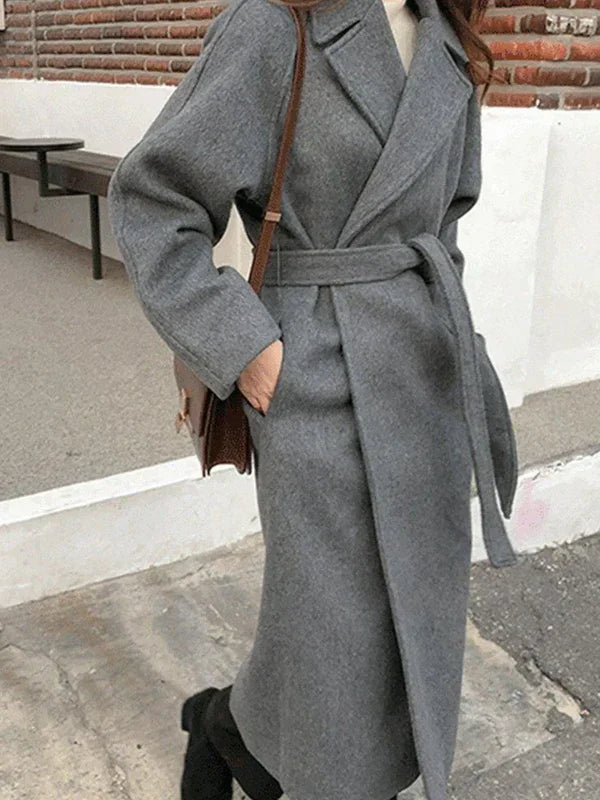 Women's long belted wrap coat in elegant winter style with waist-defining adjustable tie belt