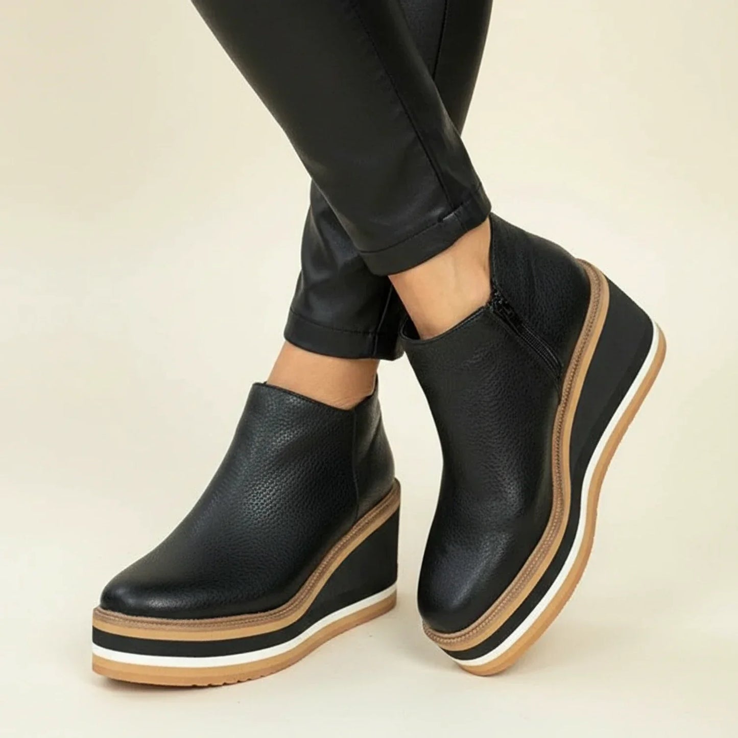 Women's black leather wedge ankle boots with sleek silhouette and height-elevating premium construction