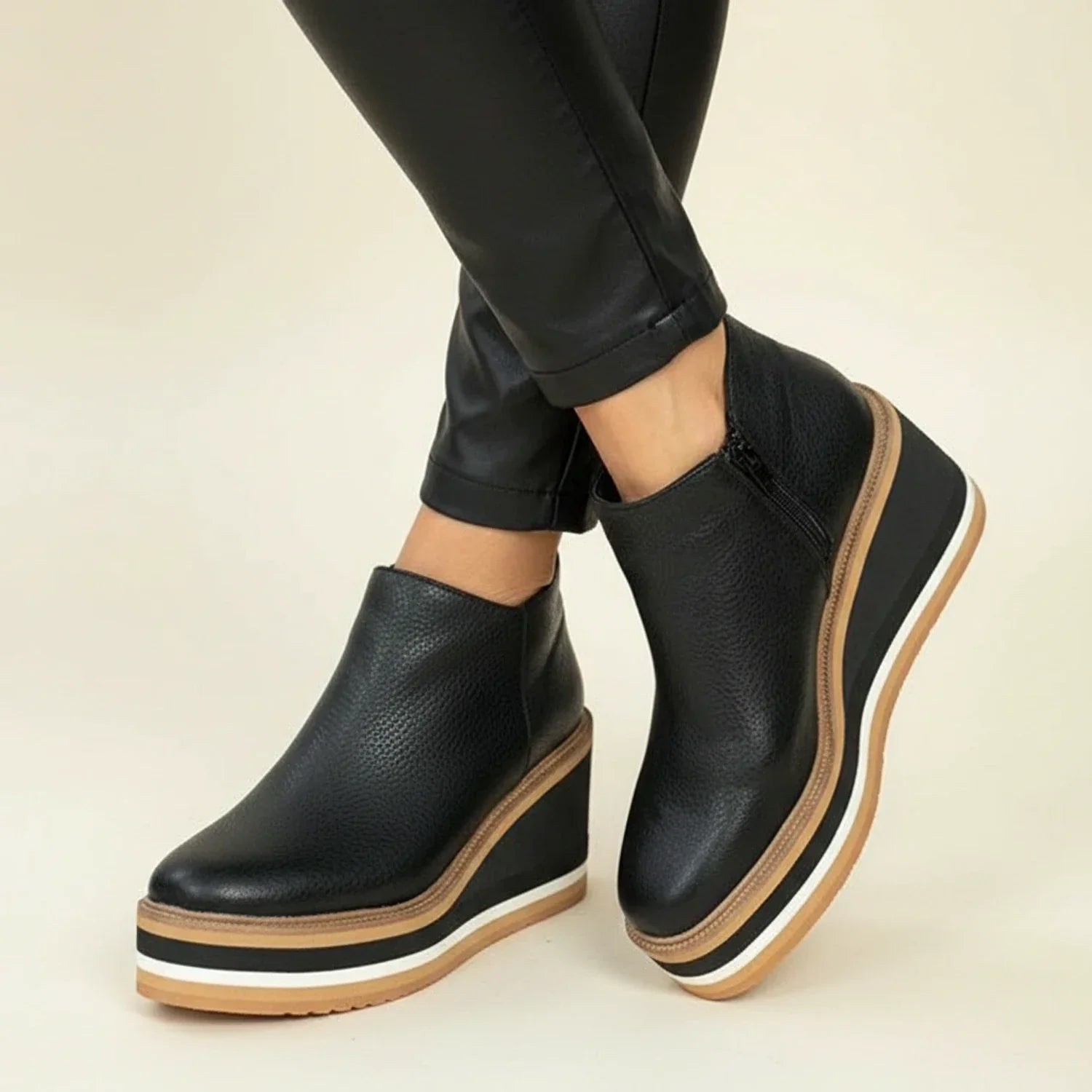 Women's black leather wedge ankle boots with sleek silhouette and height-elevating premium construction